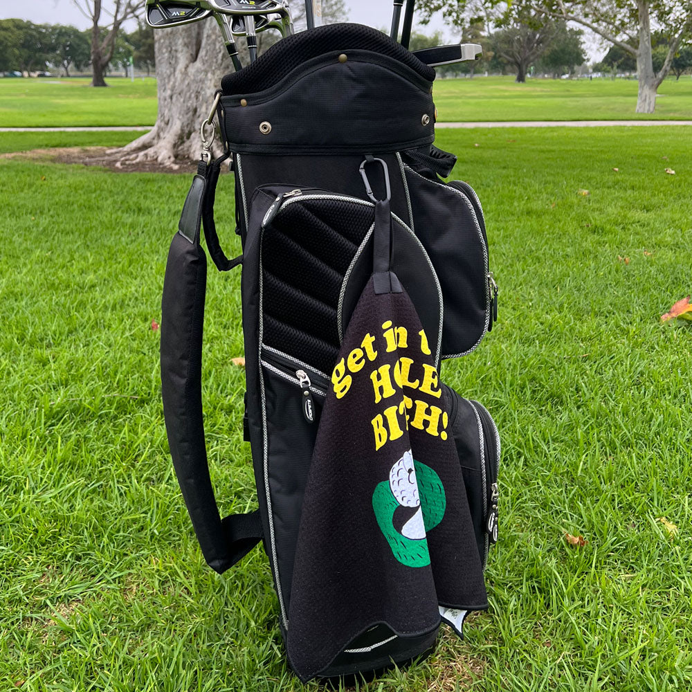 Black golf bag with a humorous towel on grass
