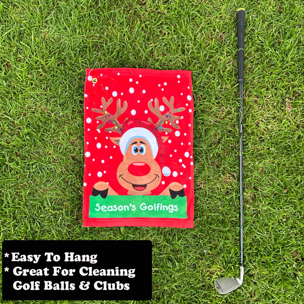 Red golf towel with reindeer design and golf club on grass