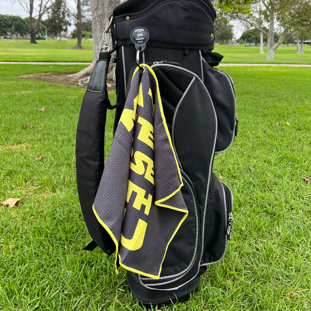 black and yellow golf towel attached to a golf bag with magnetic clip