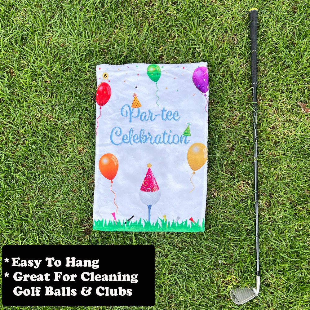 Golf towel with 'Par-tee Celebration' design on grass next to a golf club