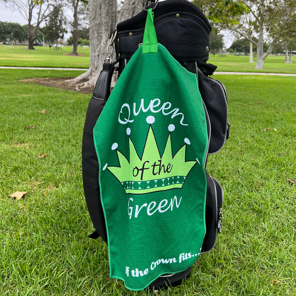 green golf towel with crown design hanging on a black golf bag