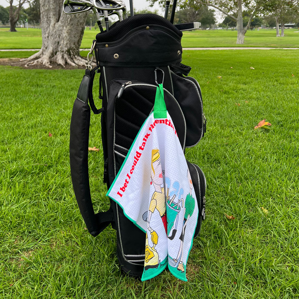 Golf bag with a humorous towel hanging out on a grassy area